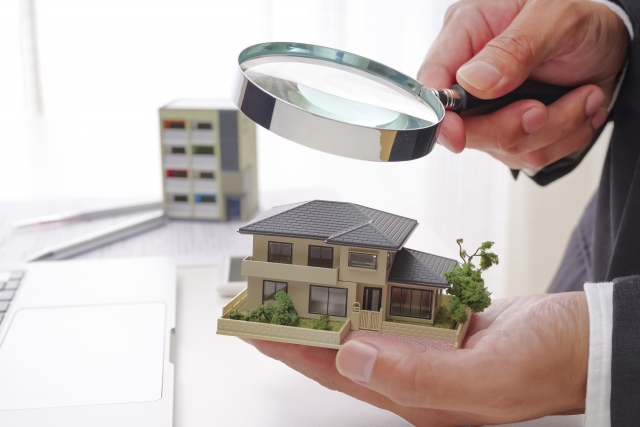 家の模型を虫眼鏡で見ている